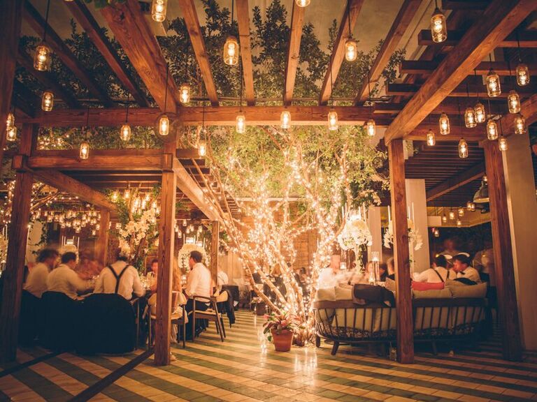 indoor wedding reception with live tree in the center of the room decorated with string lights