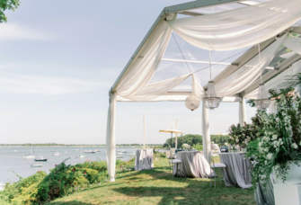Outdoor reception venue with white tent on the water