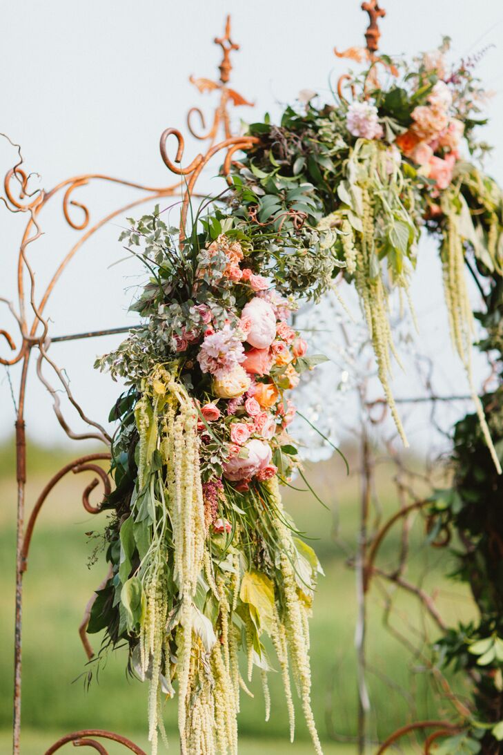Flowers were a key element in the ceremony decor and Flora Special Occasion Flowers was able to create a series of stunning arrangements that conveyed the couple’s romantic, elegant theme, while emphasizing the beauty of the natural setting. Stone urns overflowing with amaranth, roses, peonies and more framed the entrance to the aisle and small arrangements of romantic garden blooms decorated alternating rows. To create a focal point for the affair, an antique arbor was placed at the end of the aisle and decorated with a lush garland of greenery, peonies and roses, as well as a small crystal chandelier.
