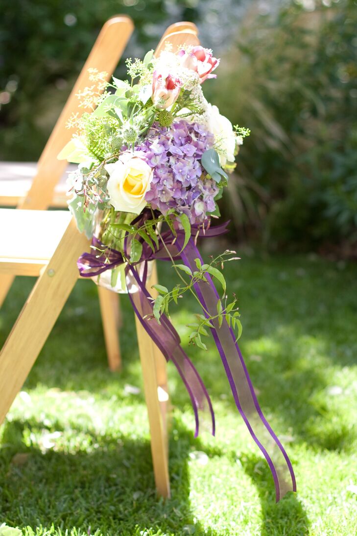 Purple hydrangeas, punk tulips, yellow roses and an abundance of greens set in ribbon-wrapped mason jars decorated the aisles during the ceremony.