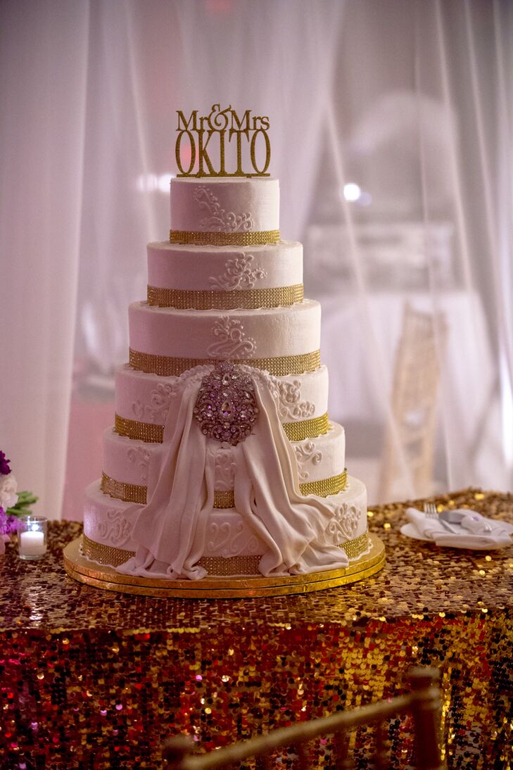 The couple cut into a grand six-tier wedding cake featuring intricate piping, fondant draping, and a crystal brooch.