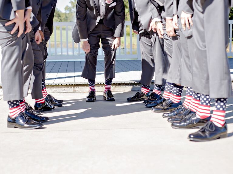 groom and groomsmen hold up pant legs to show off american flag socks