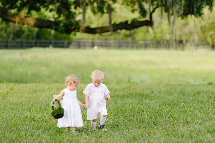 Inspired by the wedding location in James’s family’s backyard, Elizabeth and James decorated the flower girl basket with green moss, just like the live oak tree that served as the altar. She wore a white ball gown that matched Elizabeth’s look, and the ring bearer wore a white romper.