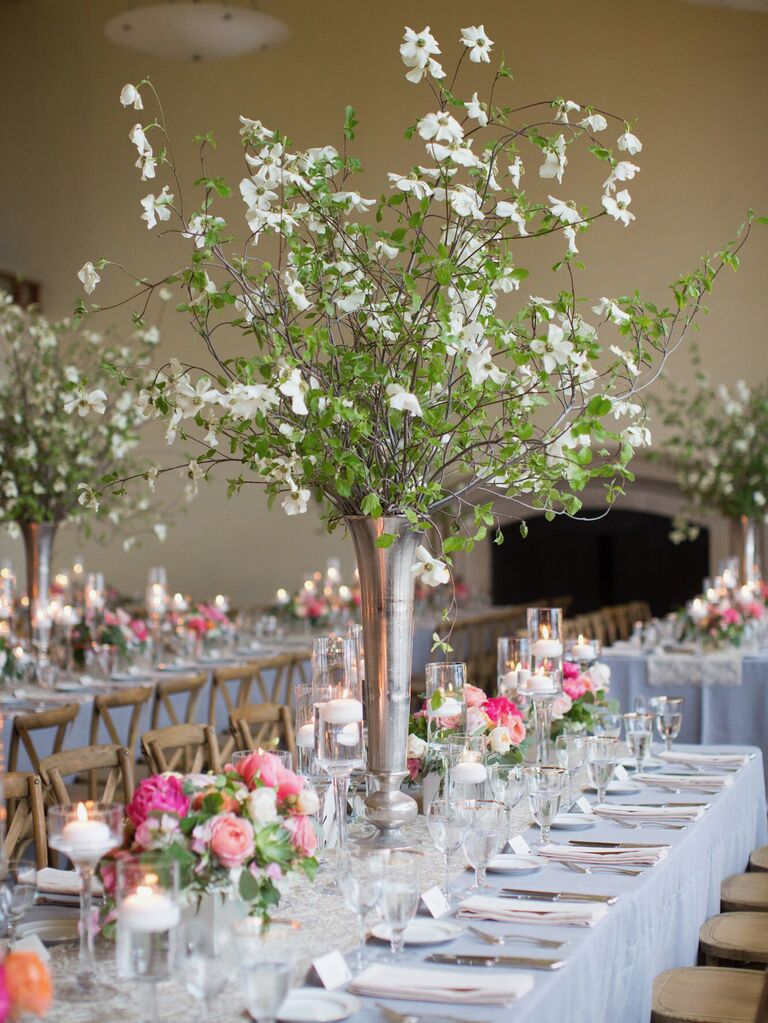 whimsical tall wedding centerpiece with white dogwood flower branches in silver trumpet vase