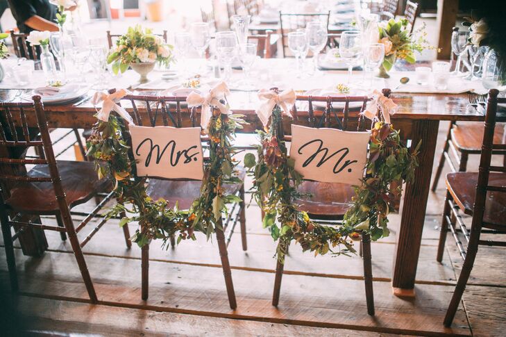 The newlyweds' seats at the reception were decorated with garlands of greens and hypericum.