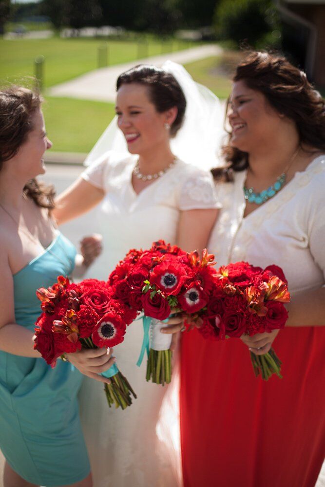 Bridesmaids were bright in blue and red and carried vibrant red anemone flower bouquets.