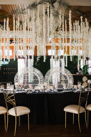 Modern Dining Table with Black Tablecloth, Wicker Sweetheart Chairs and Hanging Flowers
