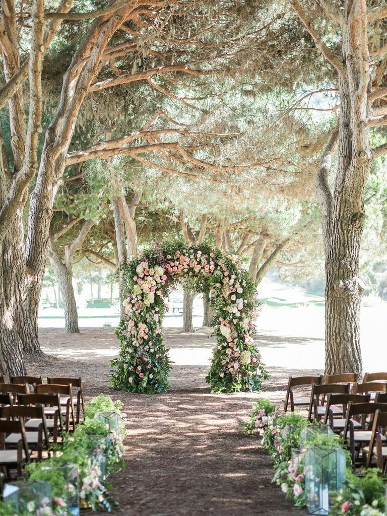 Floral arch and aisle decor at outdoor wedding ceremony