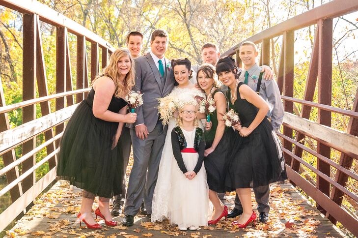 Leah's bridesmaids wore pin-up-inspired black dresses with red peep-toes to fit the retro wedding theme, while the groomsmen wore shirts and suspenders with bright teal ties. The flower girl wore a traditional white tulle dress with a bright red sash and a black sparkly bolero that resembled a retro leather jacket.