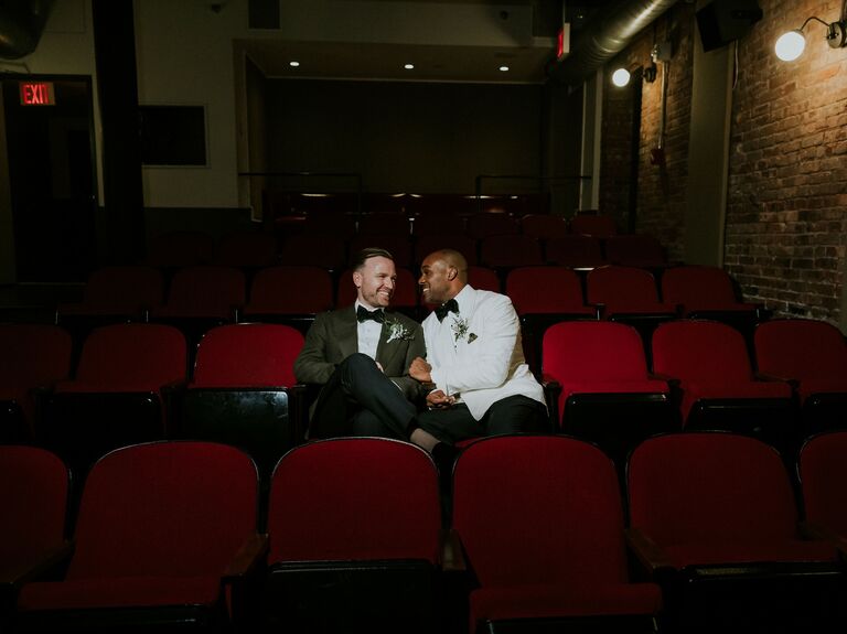 Couple wear elegant suits while sitting in a theatre. 