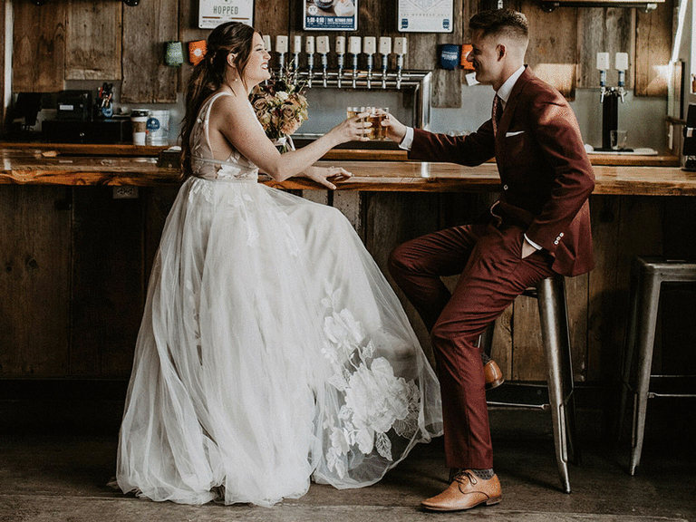Bride and groom drinking at wedding ceremony bar.