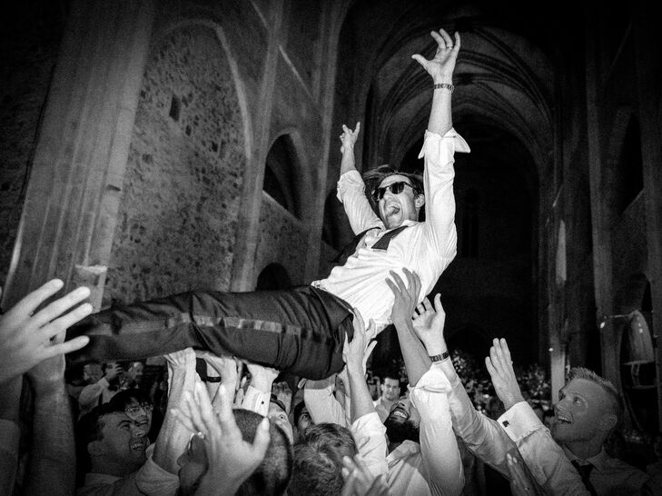 Black-and-White Photo of Guests Holding Up Groom, Crowdsurfing at Lively After Party