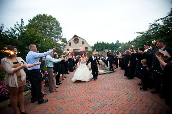 Guests line the brick pathway holding out sparklers to welcome the bride and groom to the reception. The sparklers were a fun surprise twist to an elegant, traditional theme.