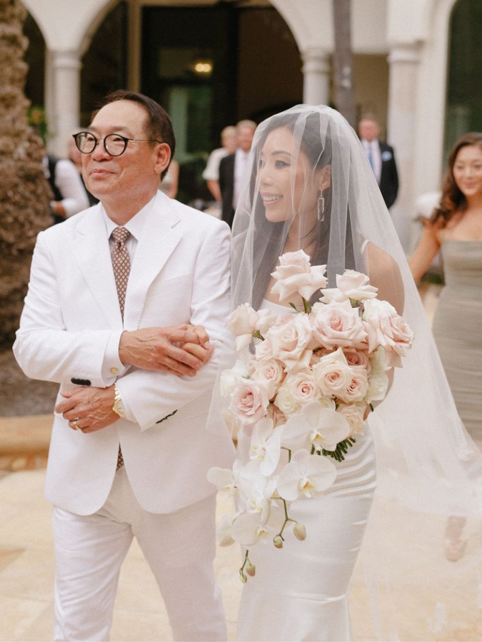 Bride holding bouquet and processing with father