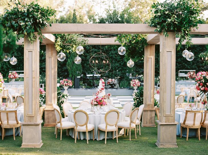Round Table With Five-Tier Wedding Cake Under Custom Pergolas, Greenery, Glass Lights