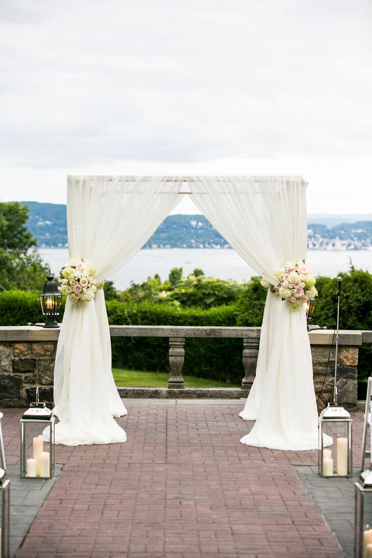 Blush and ivory-colored roses and hydrangeas were used to create two flower arrangements that flanked each side of the couple's fabric-draped chuppah.