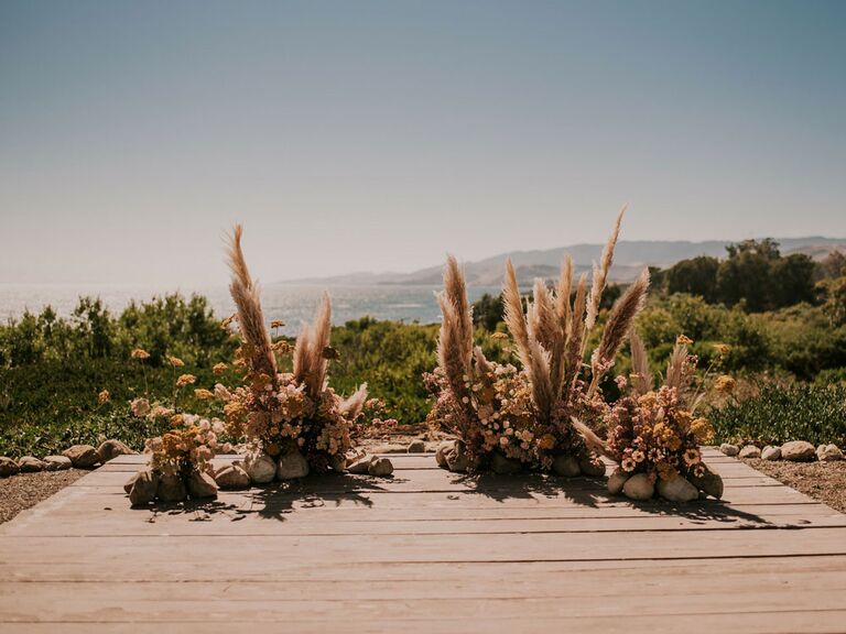 Pampas grass clusters at outdoor bohemian wedding ceremony