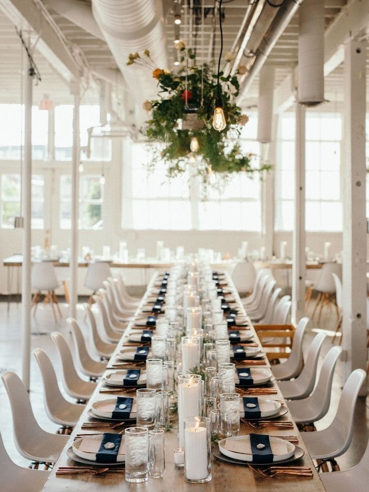long table with white pillar candles and hanging greenery