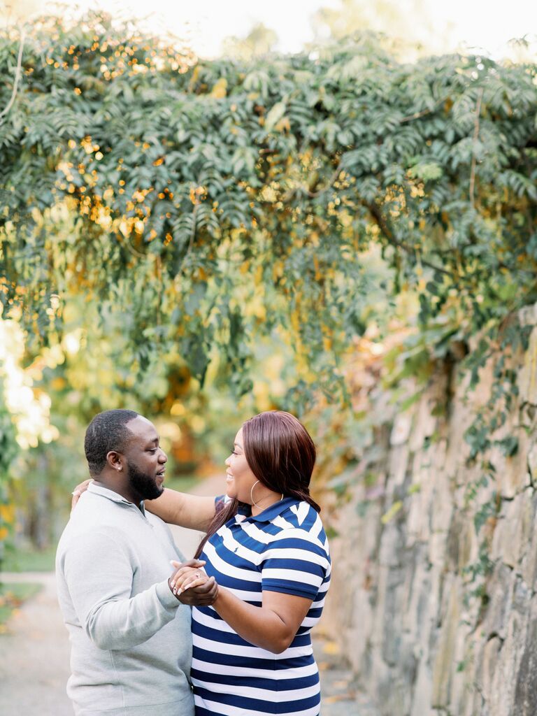 Couple embraces under vines during engagement photo shoot