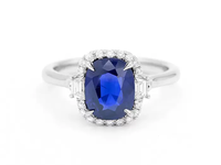 A sapphire engagement ring, the blue stone encircled by small diamonds.
