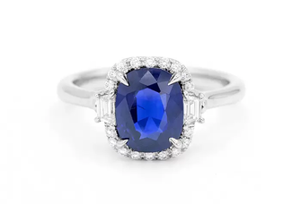 A sapphire engagement ring, the blue stone encircled by small diamonds.