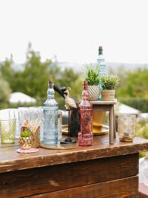Vases, Plants, Bottles in Varying Colors on Bar at Interfaith Wedding
