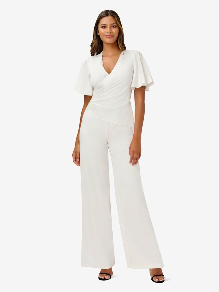 Model wears a fitted jumpsuit with fluttery sleeves. 