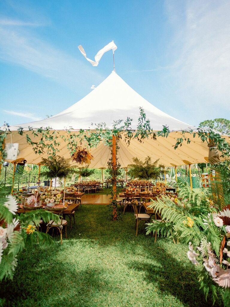 Statement wedding sailcloth tent entrance with lush florals and greenery