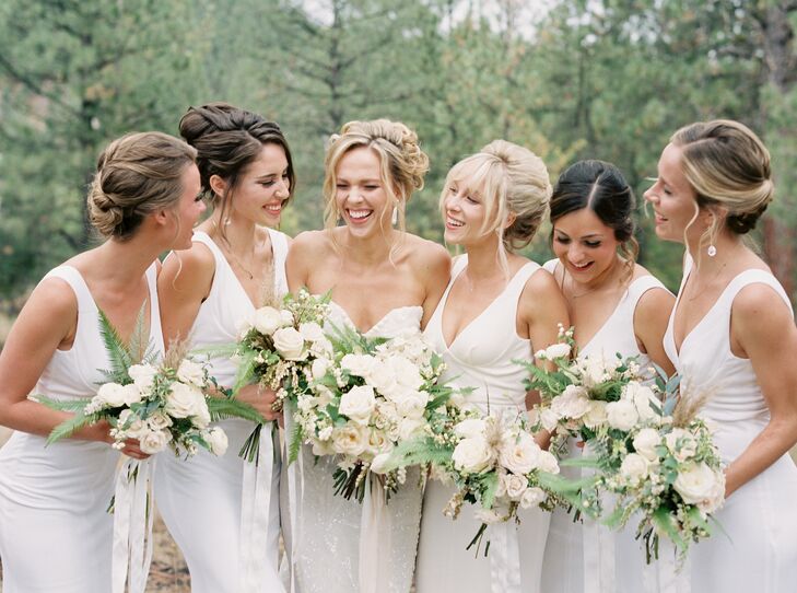 The bridesmaids wore off-white floor-length gowns with sweetheart necklines and form-fitting silhouettes.
