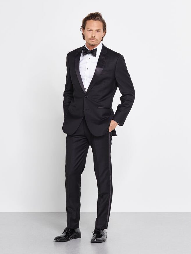 Model wears an elegant black tuxedo for a traditional wedding. 