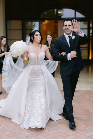 Bride in Sheer Sweetheart Wedding Dress With Overskirt and Groom in Classic Black Suit, Arm-in-Arm