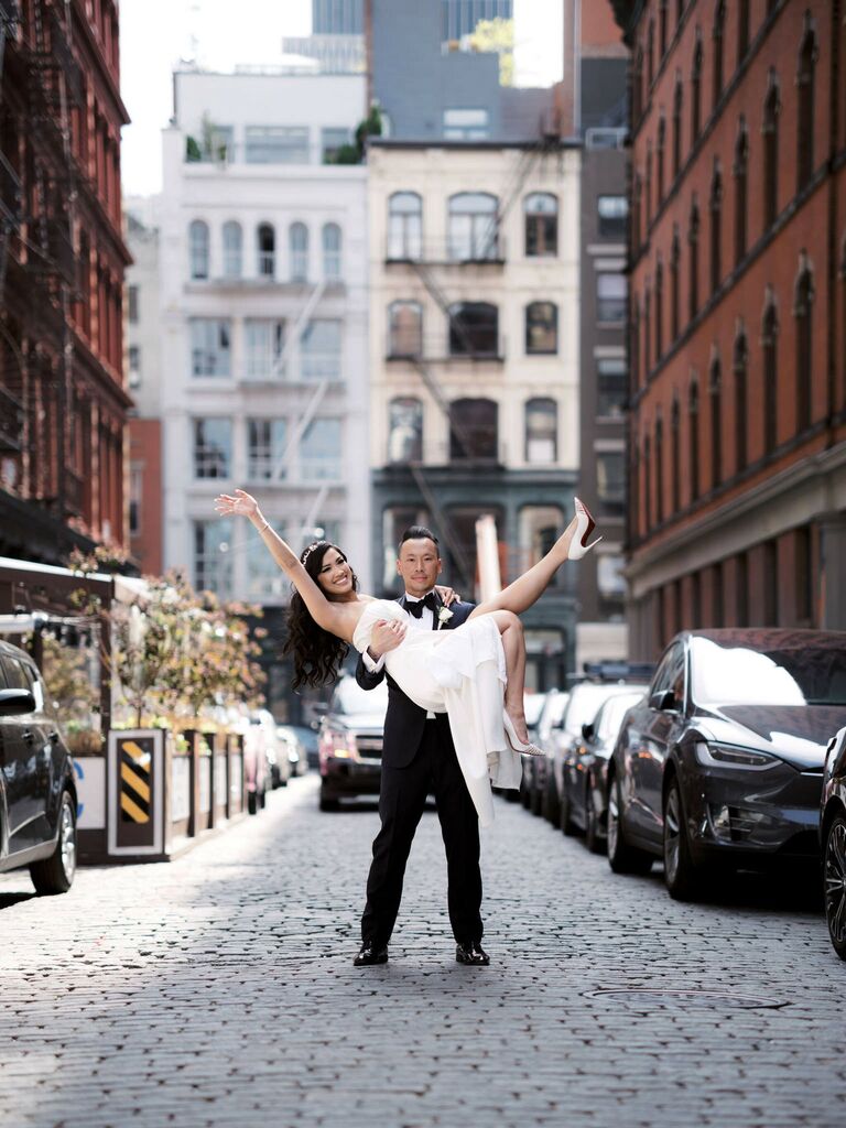 Husband holds his wife whlie she poses on a city street. 