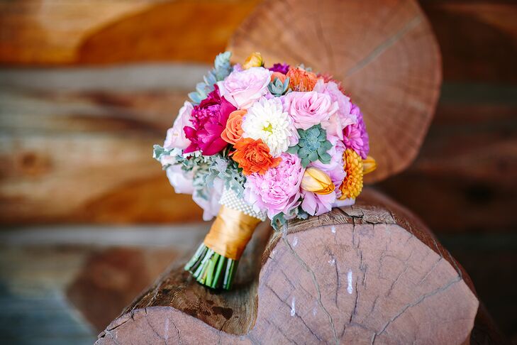 The bride carried a bouquet of pink, white, orange and gold dahlias, peonies, roses and tulips, mixed together with pops of green succulents dusty miller and wrapped in gold and pearls.