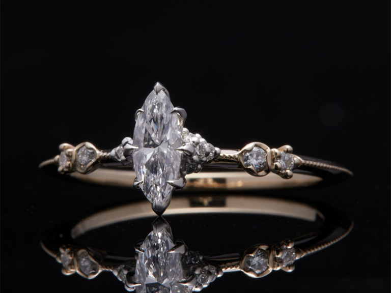 Marquise diamond center stone with prongs and side diamond accents on thin band