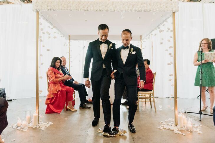 Grooms breaking the glass under chuppah at Jewish wedding ceremony