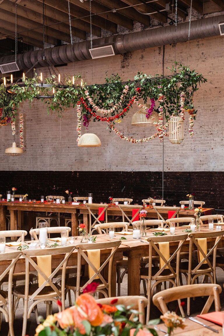 Loft wedding reception with greenery chandelier and cross-back chairs
