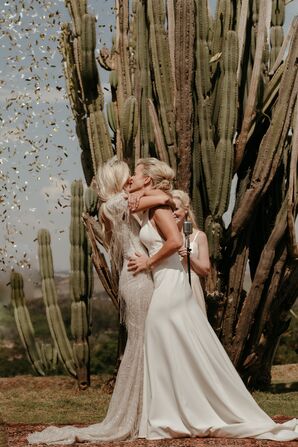 Bride in Beaded Gown Kissing Bride in Sleek Dress at Desert Ceremony, Cactus and Confetti