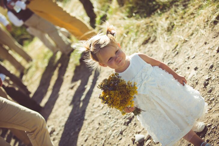 The flower girl wore a white A-line dress accented with a giant bow on the front and decorated with little white rosettes on the skirt. She carried a yellow wildflower bouquet that the bridesmaids had arranged the day before the wedding.