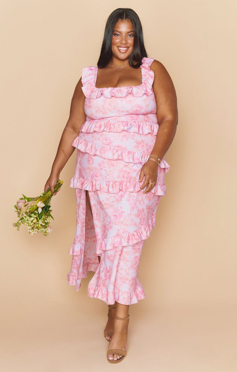 Model wears a pink floral gown with ruffled hems. 