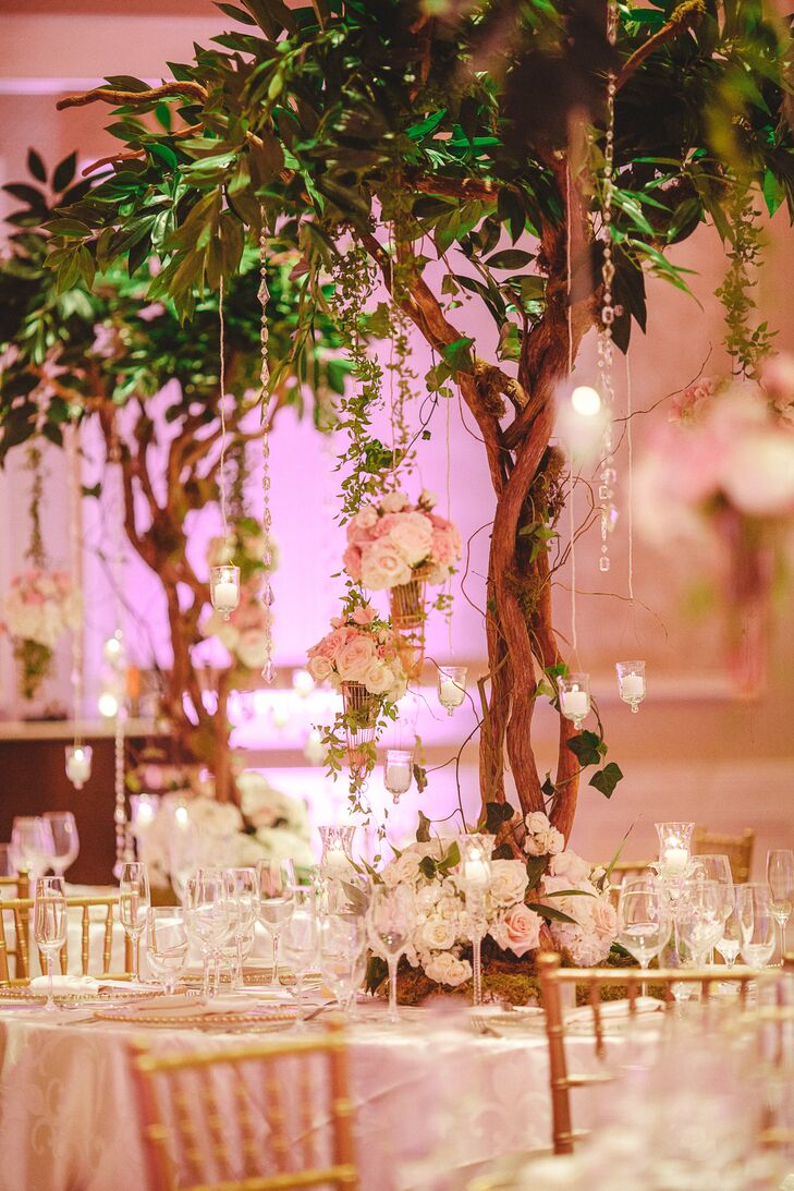 The centerpieces on the round tables were six-foot moss-covered structures made of tree branches embellished with fresh greens, ivy, hanging crystals, votives and nests of pink lovebirds.