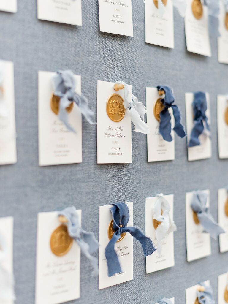 wedding escort cards decorated with gold wax seals and raw silk ribbons in varied light blue colors