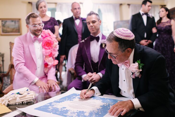 Jewish Grooms in Bold, Pink-and-Purple Tuxes Watch as Rabbi With Colorful Kippah Signs Ketubah