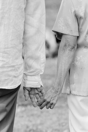 Black-and-White Photo, Couple Holding Hands on 50th Wedding Anniversary During Vow Renewal