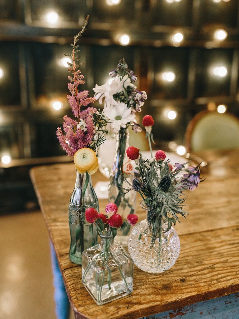 boho fall wedding centerpiece with mismatched glass jars and red, yellow and purple wildflowers