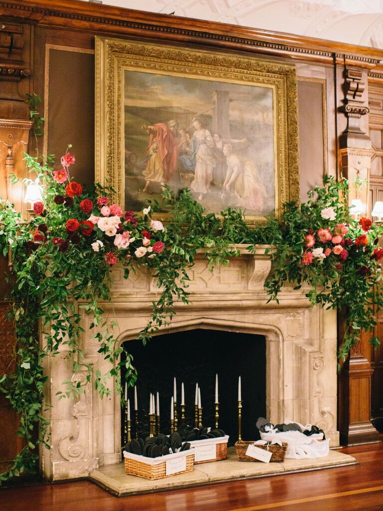 wedding fireplace decor with greenery vines and pink and red roses on top of stone mantel