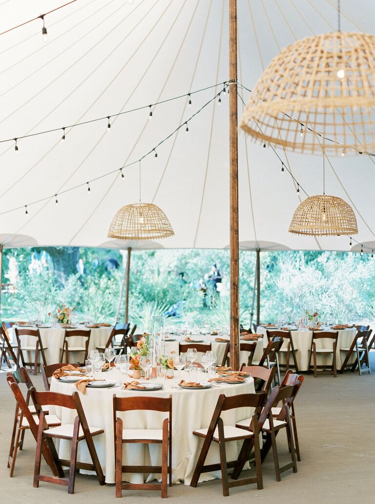 Tented wedding reception with wood folding chairs and woven chandeliers