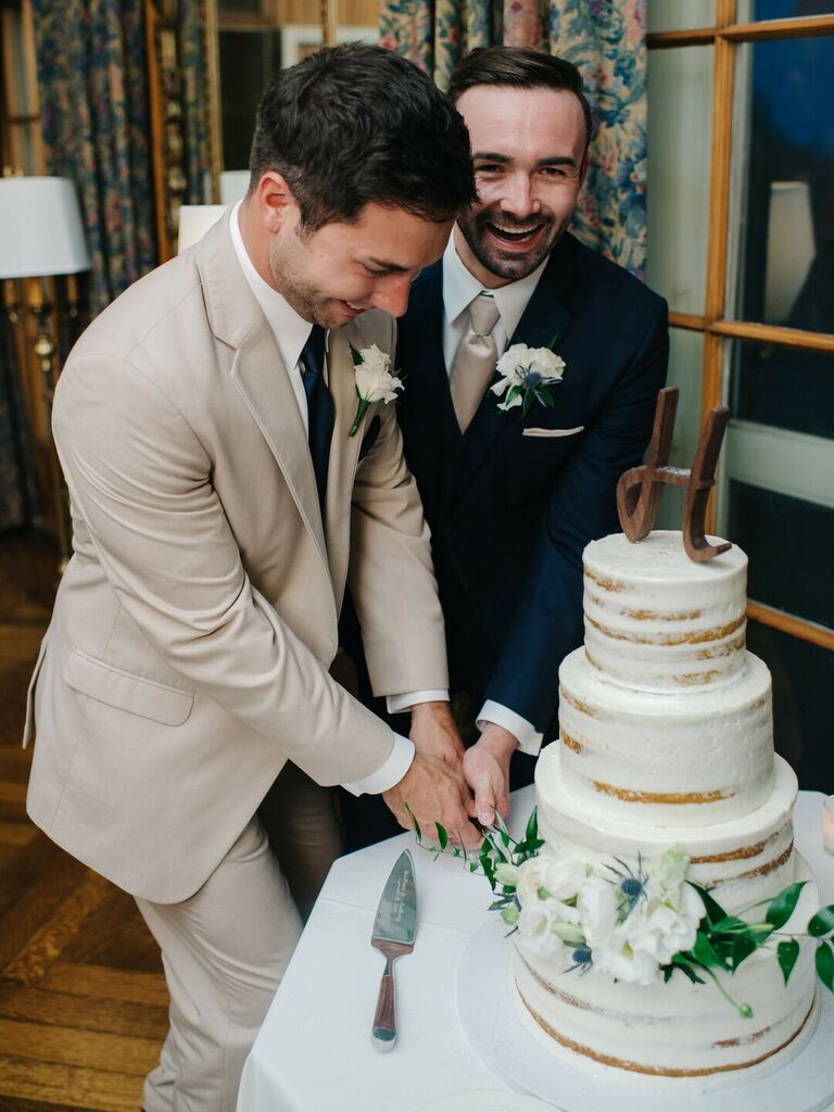 Grooms cutting wedding cake together. 