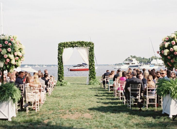 Overlooking the water, the ceremony site was decorated with vintage furniture rentals and a lush boxwood arbor with sheer curtains.