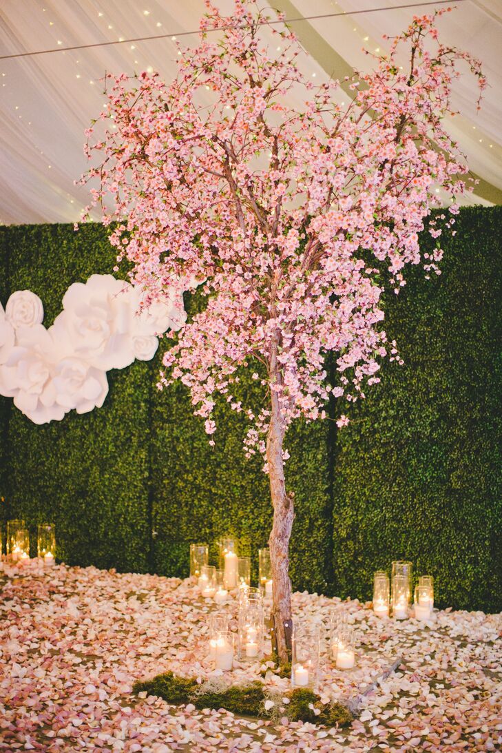 The cherry blossom trees had the floors entirely covered in its pink petals, decorating the area around the sweetheart table. Candles in glass cylinder vases that ranged in height added a romantic ambience, also scattered on the ground.