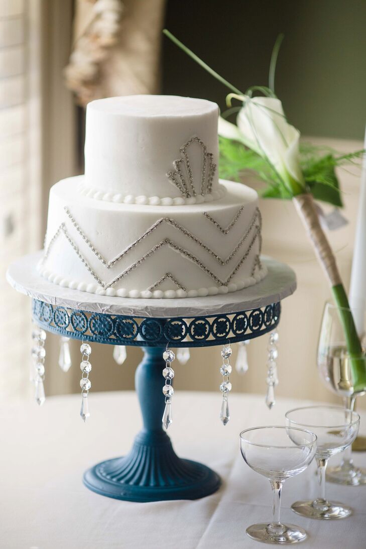 The art deco-inspired wedding cake really embodied the theme of the day. Two white tiers decorated with the vintage design sat on top of a blue cake stand with dangling crystals.